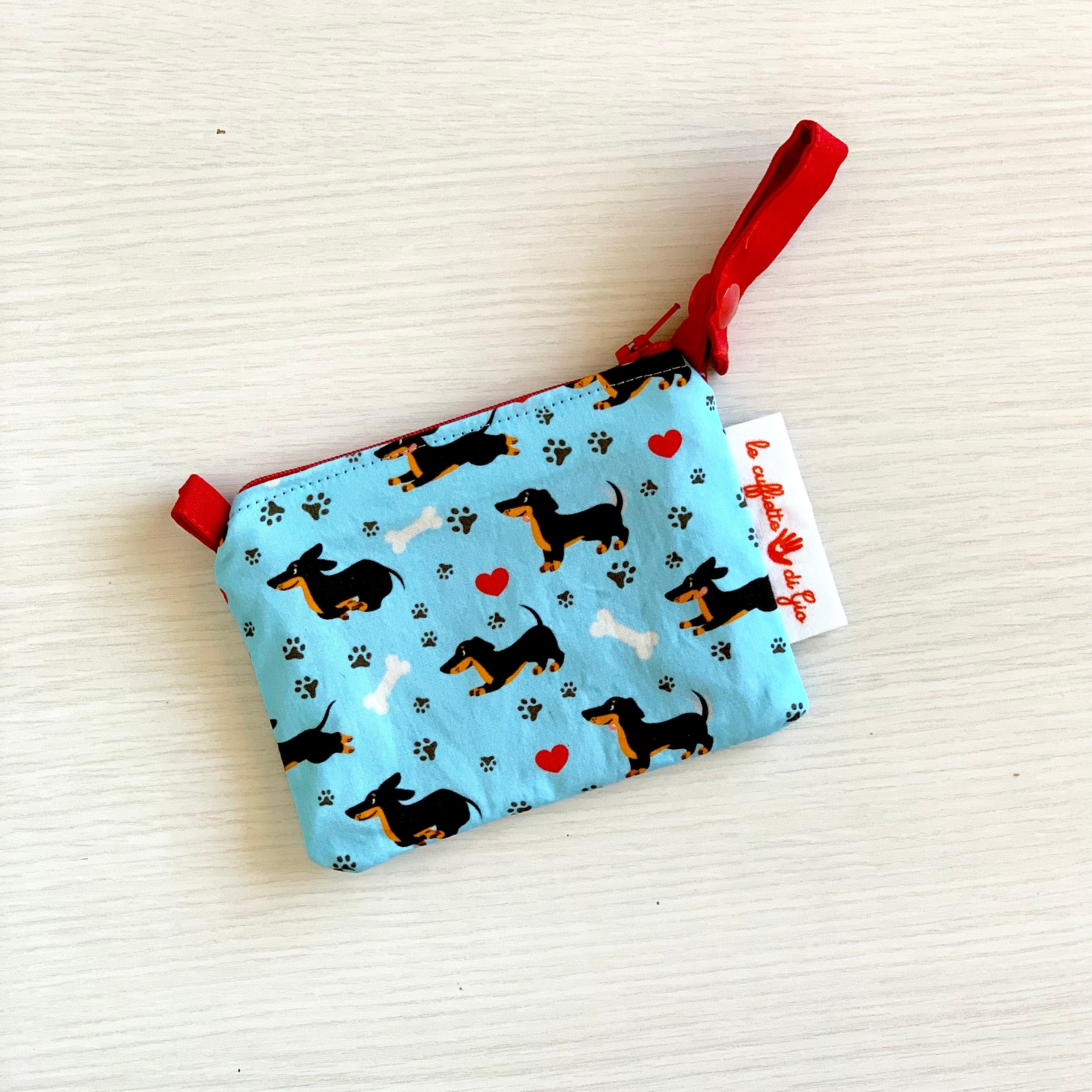 Un simpatico bassotto corre felice fra impronte di zampette, ossi da sgranocchiare e cuoricini in una combinazione di colori vincente!