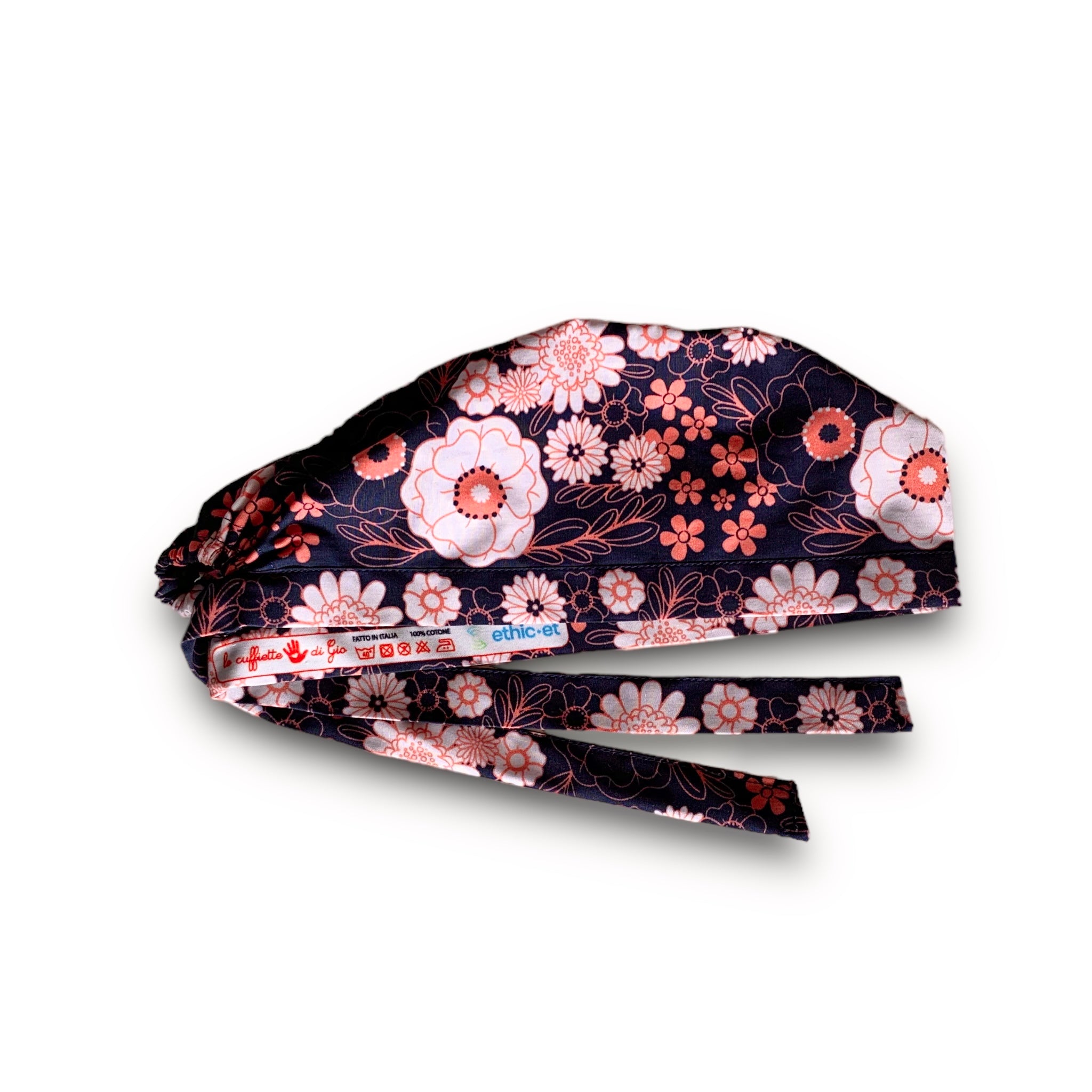 Una fantasia floreale con due soli colori: bianco latte e salmone. Fiori grandi e piccoli, margherite e peonie, si alternano a fogliame disegnato solo nel contorno per dare leggerezza e risaltare il contrasto con lo sfondo blu scuro