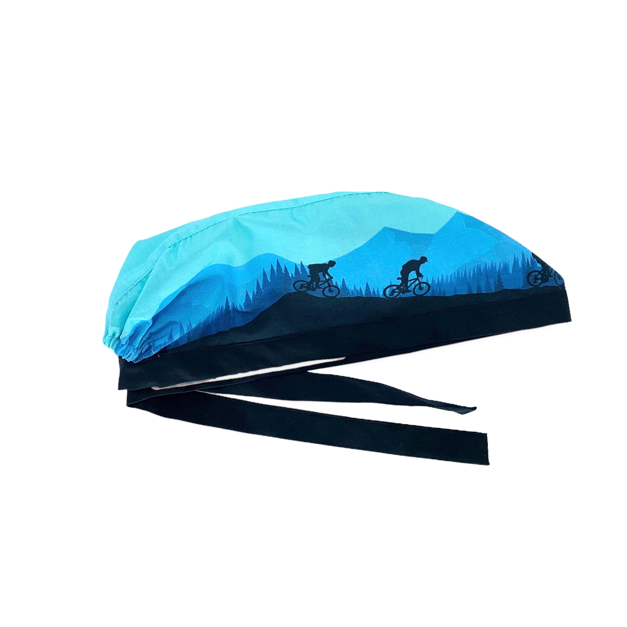 Cuffietta chirurgica che rappresenta una gita in bicicletta fra boschi e montagne; colore prevalente azzurro cielo con figure blu di ciclisti montagne alberi nel retro blu medio