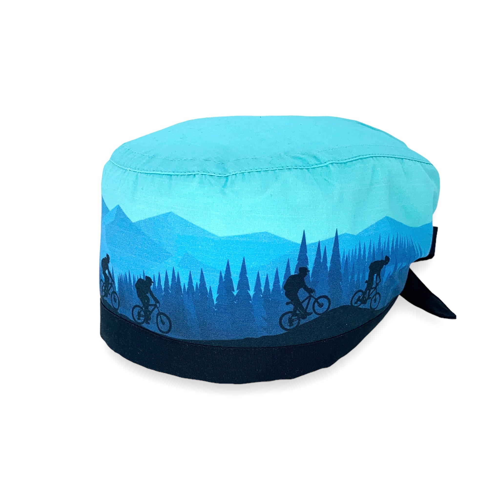 Cuffietta chirurgica che rappresenta una gita in bicicletta fra boschi e montagne; colore prevalente azzurro cielo con figure blu di ciclisti montagne alberi nel retro blu medio