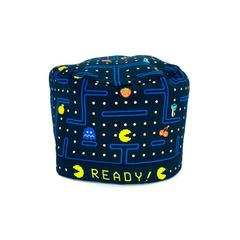 Cuffietta chirurgica che riproduce il videogioco in cui una pallina gialla mangia delle pedine ed è inseguita da piccoli fantasmi colorati che possono eliminarla. Nel percorso nero ci sono dei separatori blu ed altri elementi del gioco