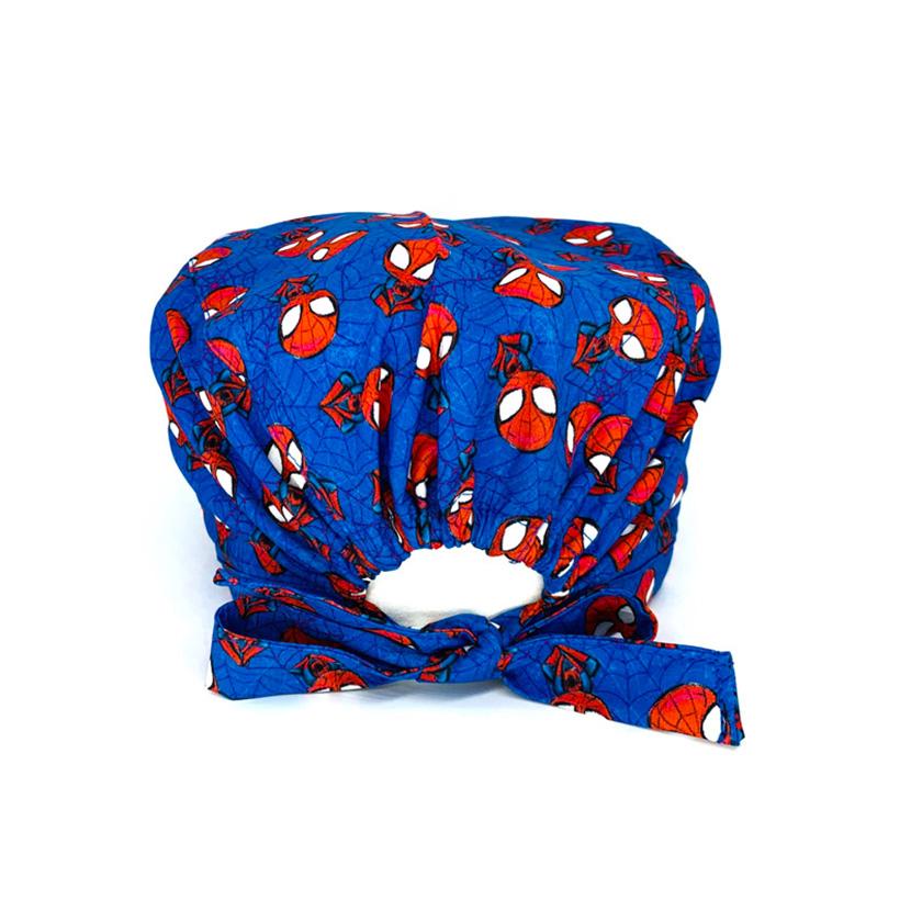 Cuffietta chirurgica con personaggio rosso appeso a testa in giù a ragnatele, con piccoli ragni neri, sfondo blu cobalto con ragnatele più scure