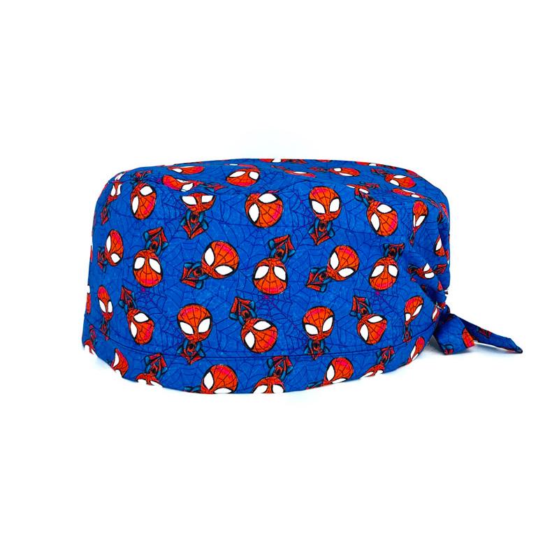 Cuffietta chirurgica con personaggio rosso appeso a testa in giù a ragnatele, con piccoli ragni neri, sfondo blu con ragnatele più scure