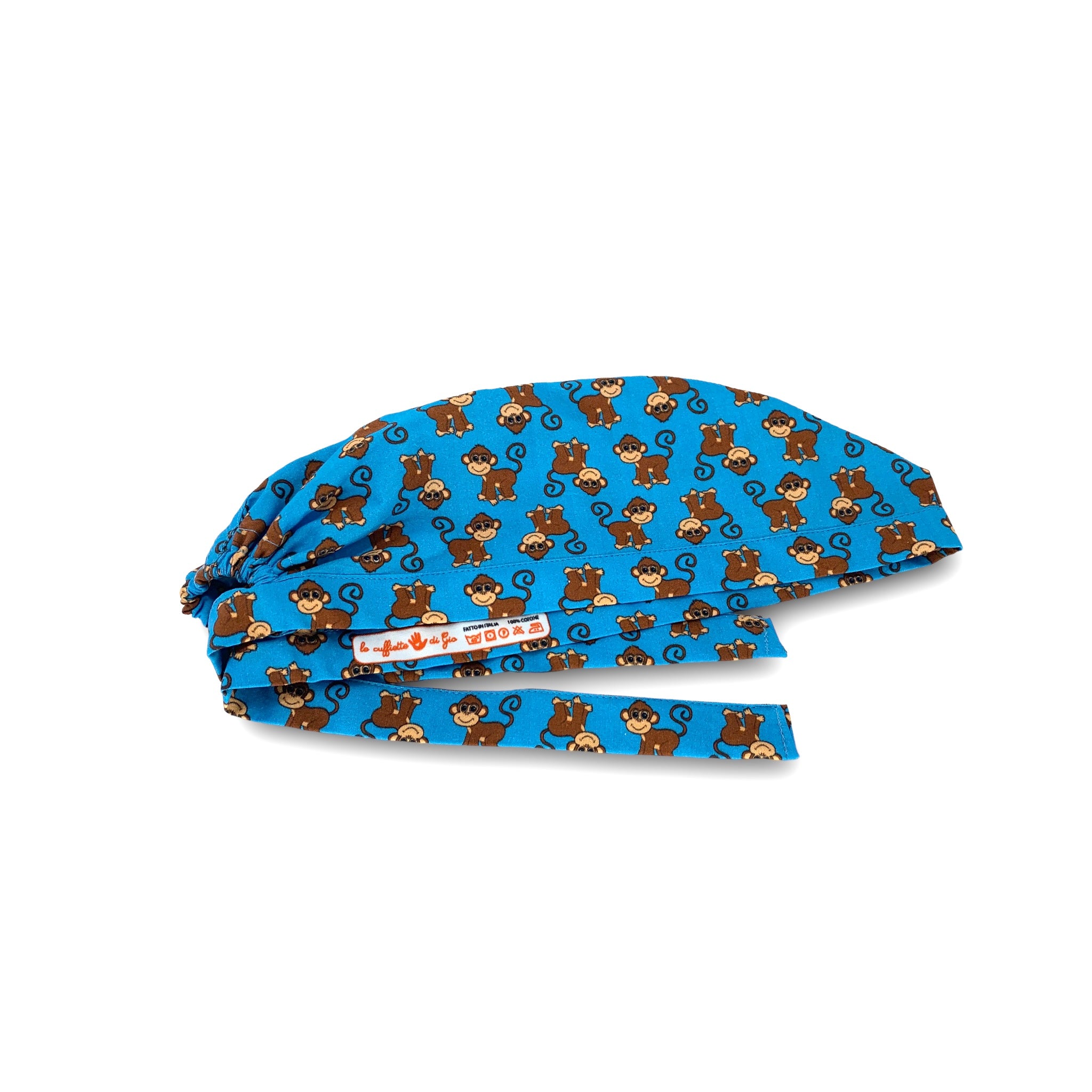 Cuffietta chirurgica con simpatiche scimmiette marroni, sorridenti e con la coda lunga arricciata, alternate a testa in giù o diritte; sfondo azzurro intenso