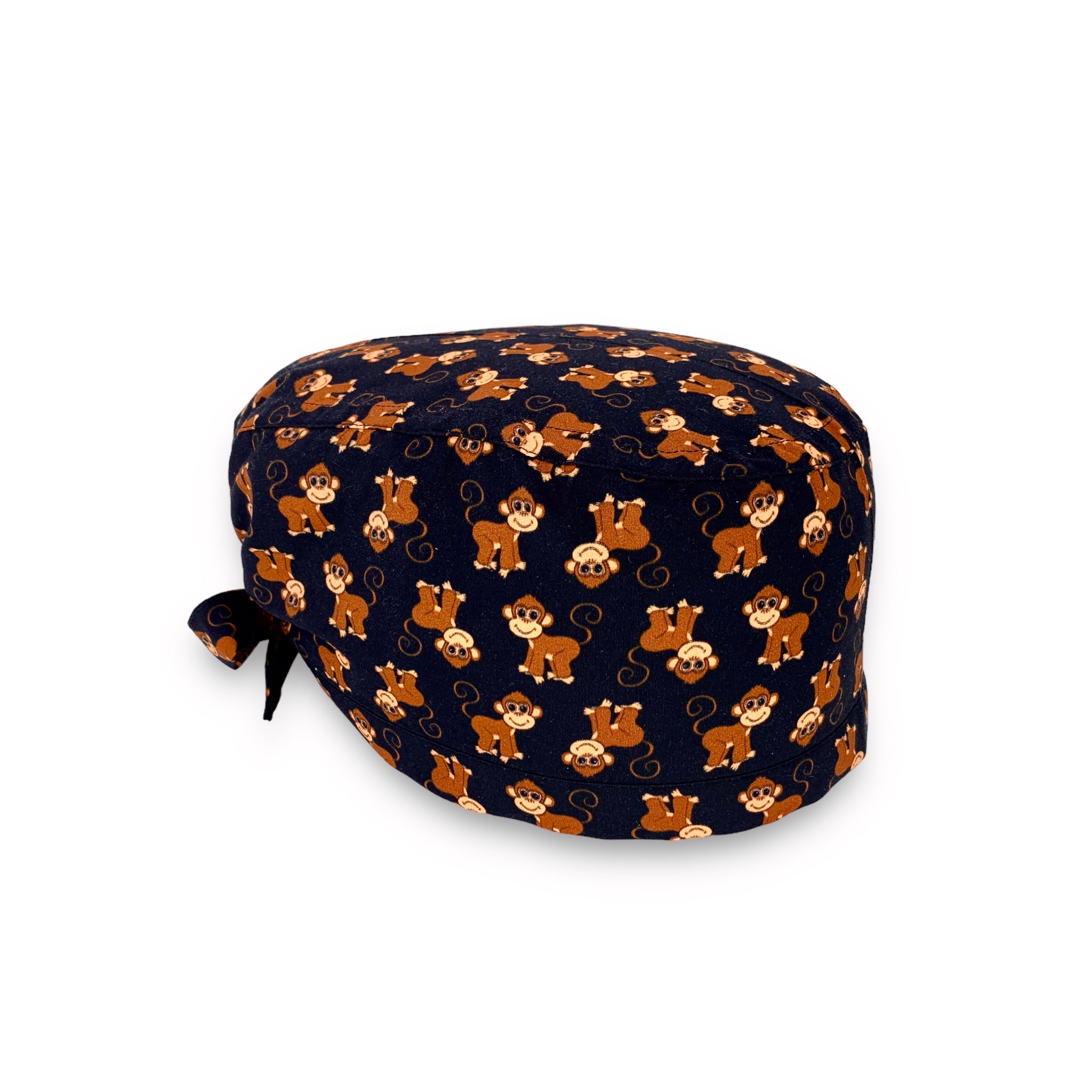 Cuffietta chirurgica con simpatiche scimmiette marroni, sorridenti e con la coda lunga arricciata, alternate a testa in giù o diritte; sfondo nero
