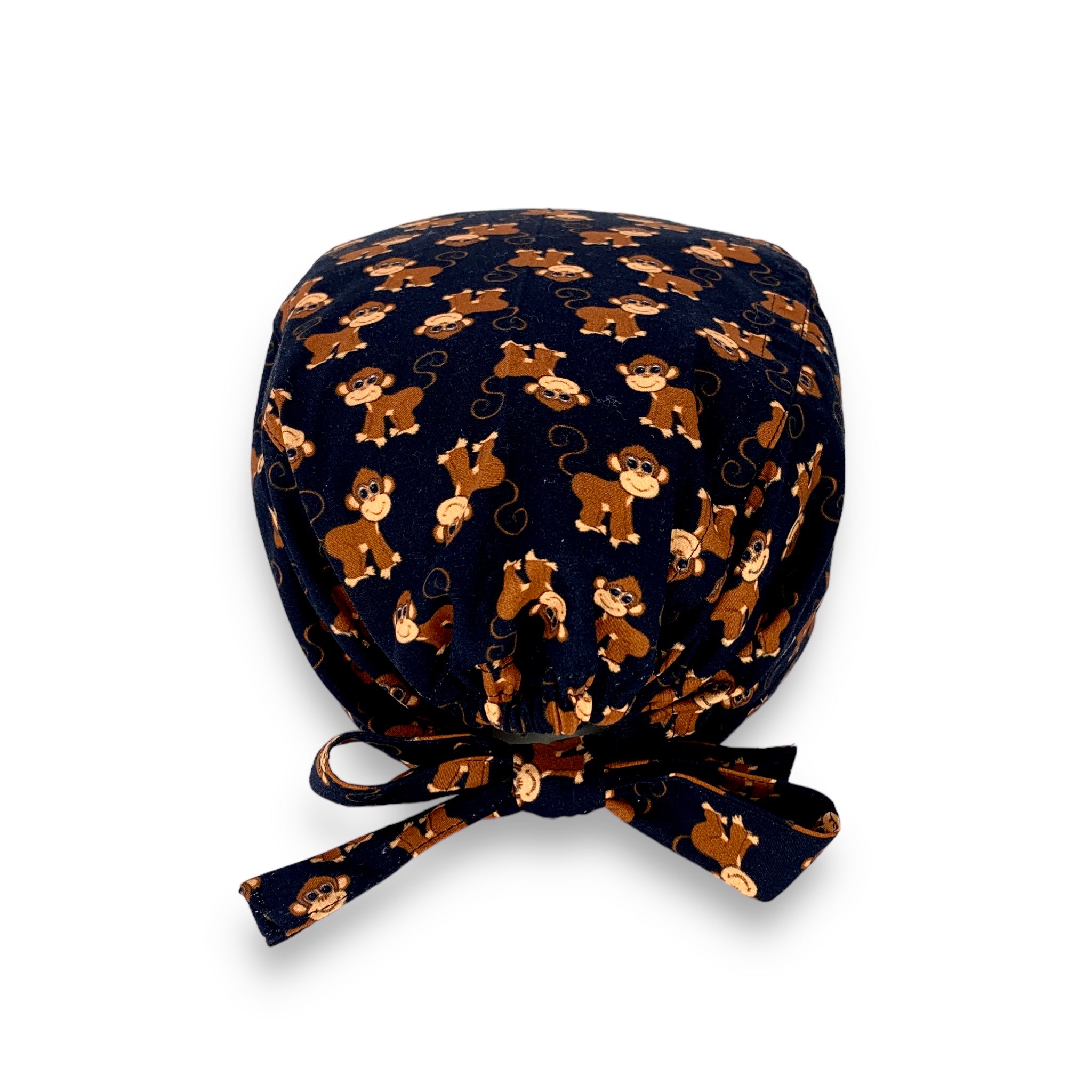 Cuffietta chirurgica con simpatiche scimmiette marroni, sorridenti e con la coda lunga arricciata, alternate a testa in giù o diritte; sfondo azzurro intenso