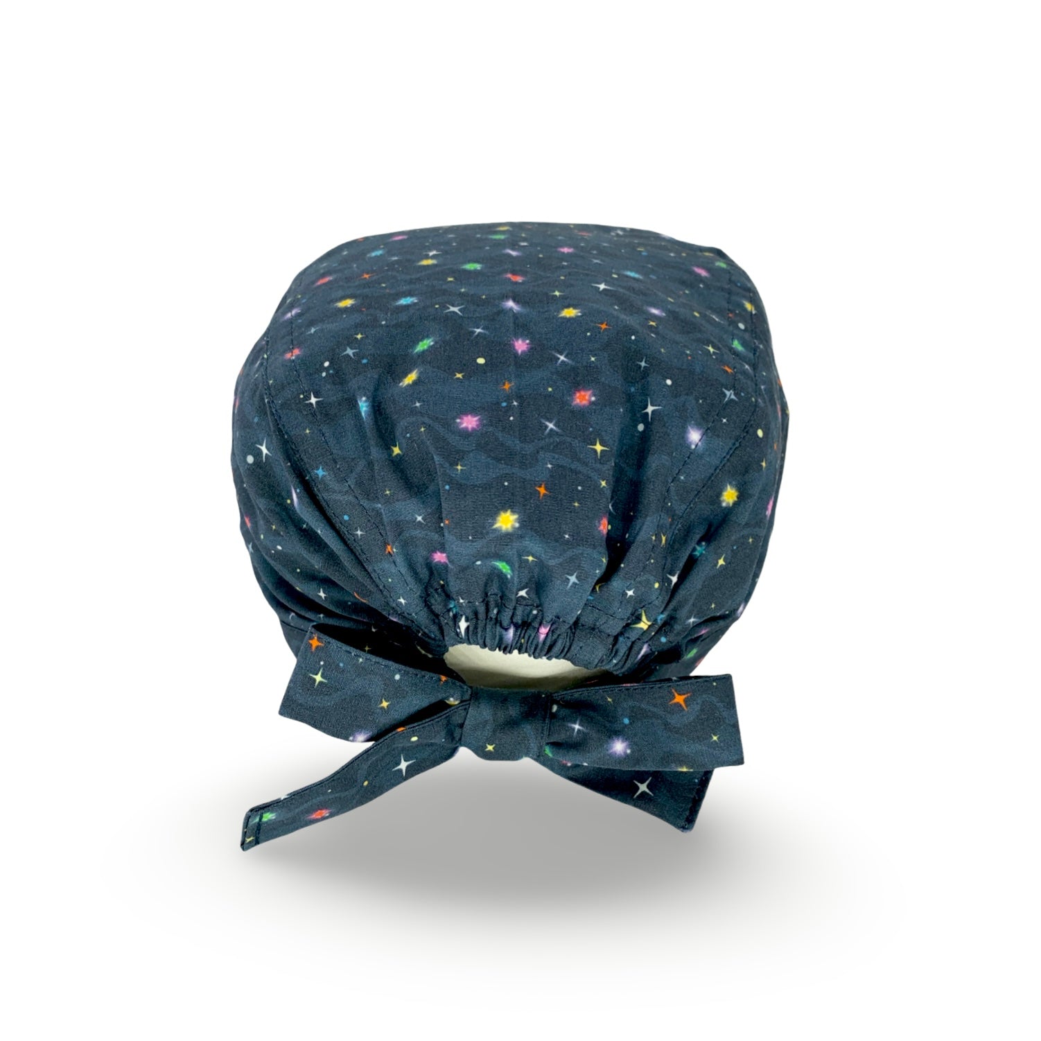 Cuffietta chirurgica con tante piccole stelline colorate che brillano su uno sfondo blu scuro, con onde tono su tono che simulano nubi spaziali.