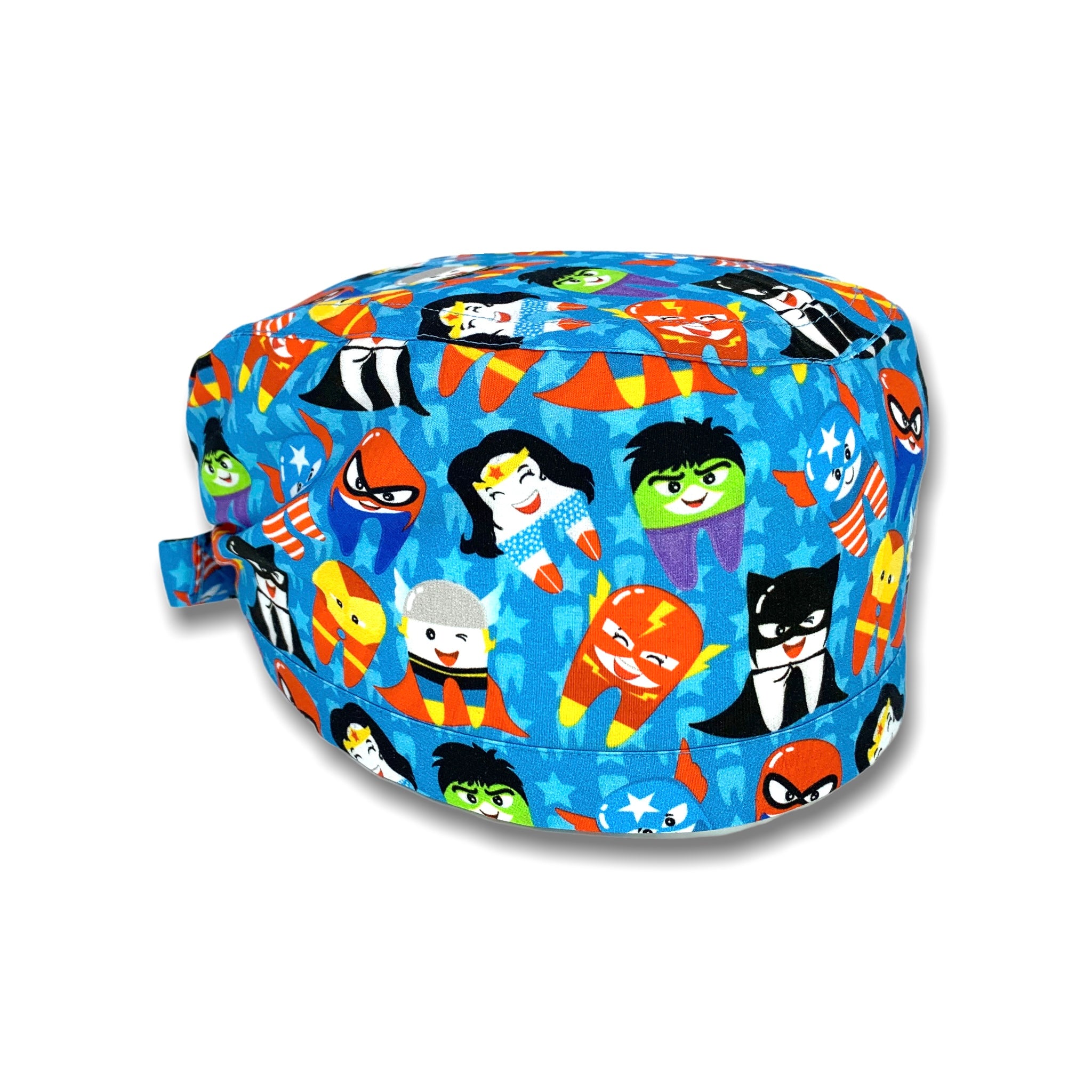 Cuffietta chirurgica con denti travestiti da super eroi; sullo sfondo azzurro intenso e un pattern di stelline e dentini tono su tono