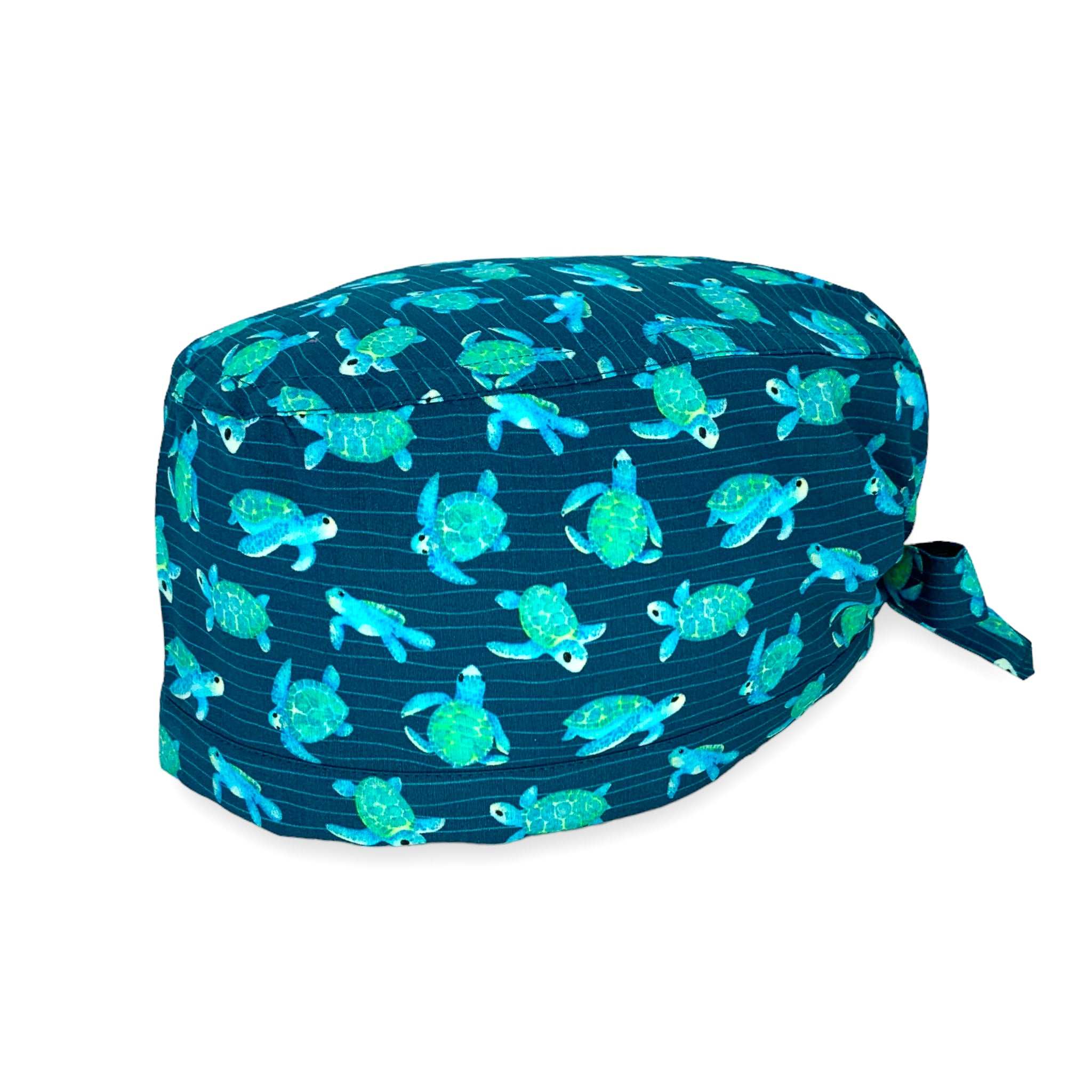Cuffietta chirurgica blu avio con tartarughe disegnate ad effetto acquerello nei toni del turchese, sullo sfondo piccole righe ondulate che ricordano la profondità del mare