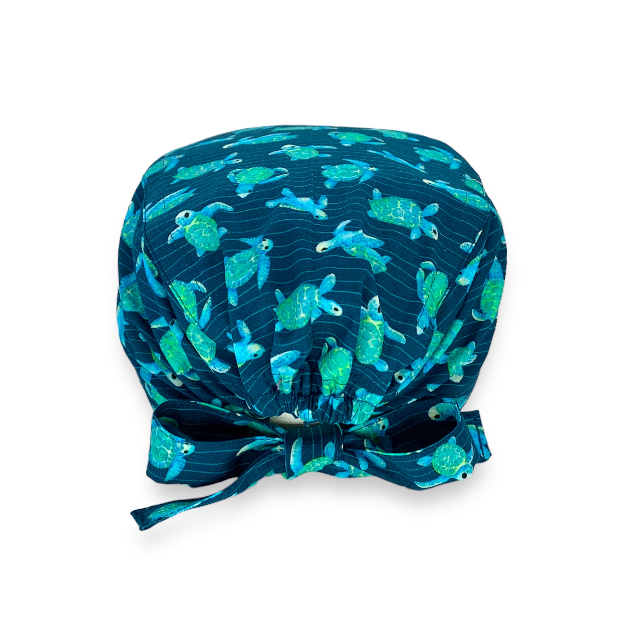 Cuffietta chirurgica blu avio con tartarughe disegnate ad effetto acquerello nei toni del turchese, sullo sfondo piccole righe ondulate che ricordano la profondità del mare