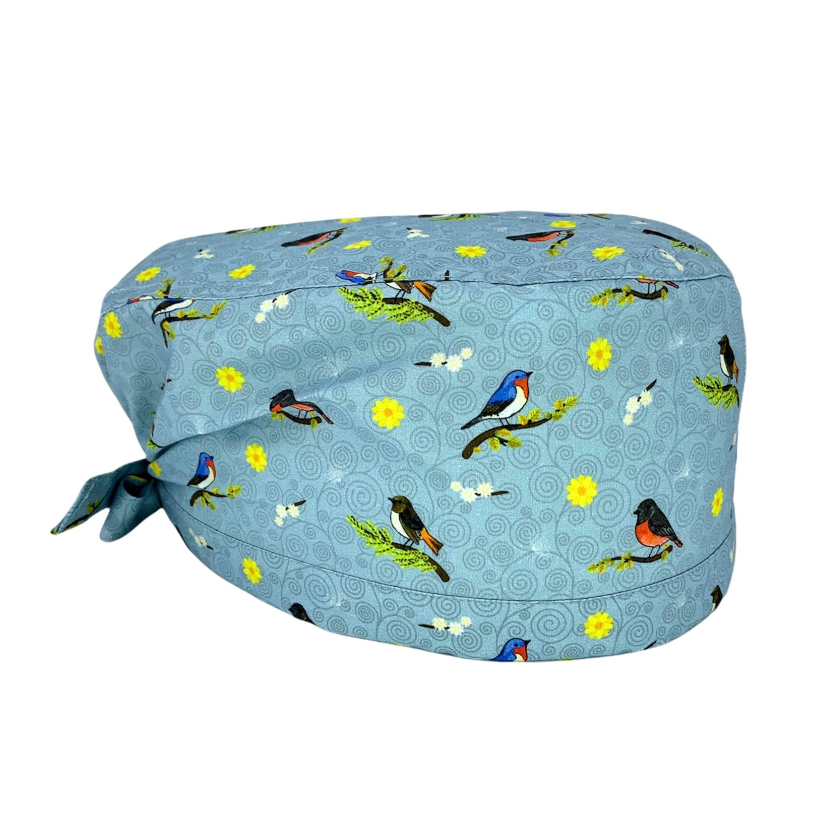 Cuffietta chirurgica grigio ceruleo con piccoli uccellini su rami, fiorellini gialli e bianchi e sullo sfondo piccoli vortici tono su tono. La cuffietta indossata dalla Dott.ssa Teddy Altman in Grey's Anatomy.