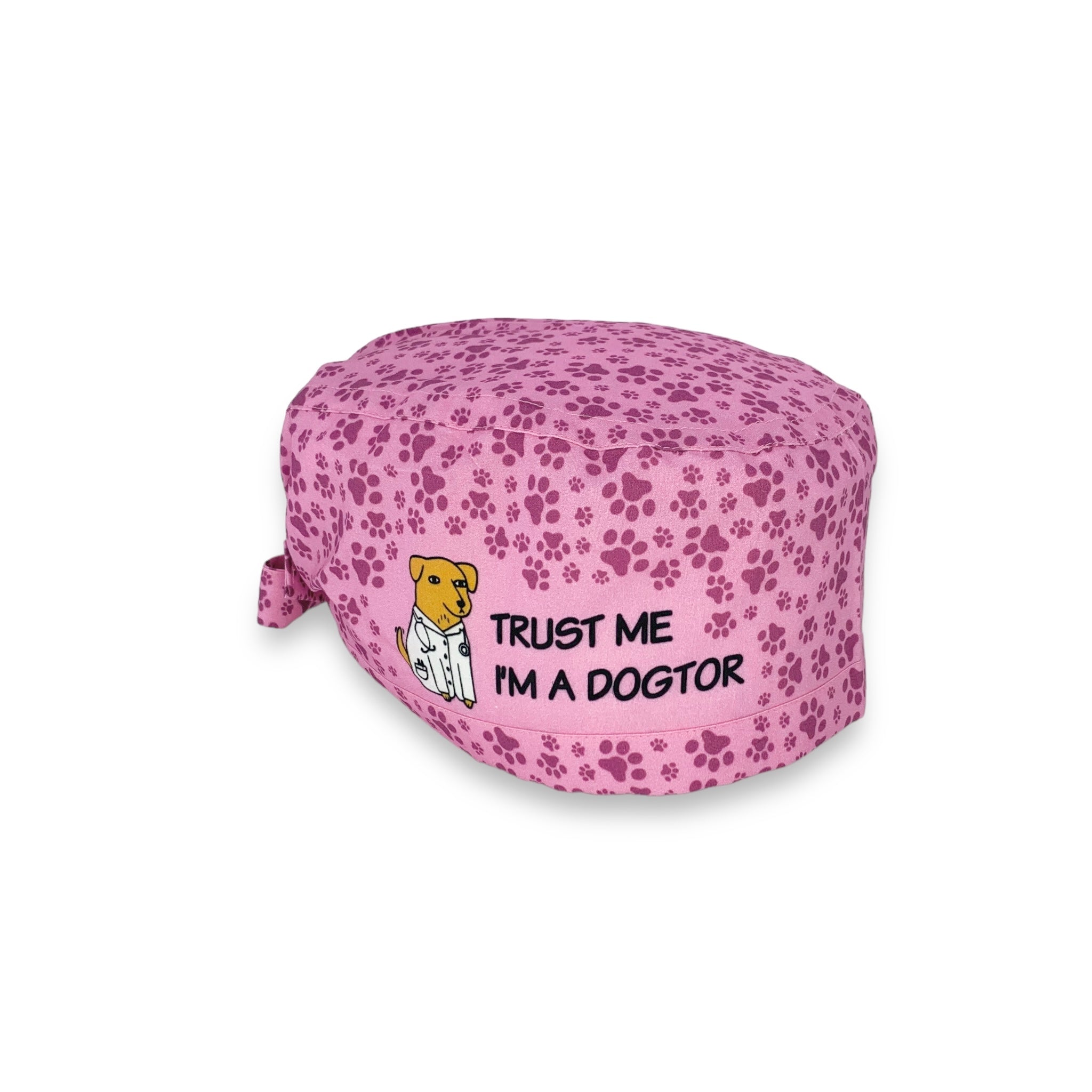 Una cuffietta simpaticissima! Mille impronte di cane tono su tono su UNA BASE ROSA INTENSO SU cui si apre uno spazio con disegnato un cane con un camice medico e uno stetoscopio al collo e la frase "TRUST ME I'M A DOGTOR"