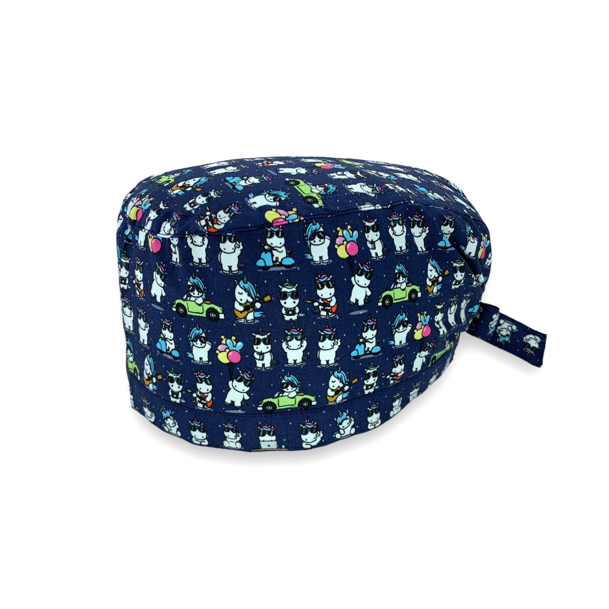 Cuffietta chirurgica con piccoli unicorni bianchi disegnati in stile kawaii, in varie posizioni mollto buffe: in macchina, in scooter, mentre suona la chitarra. Sfondo blu