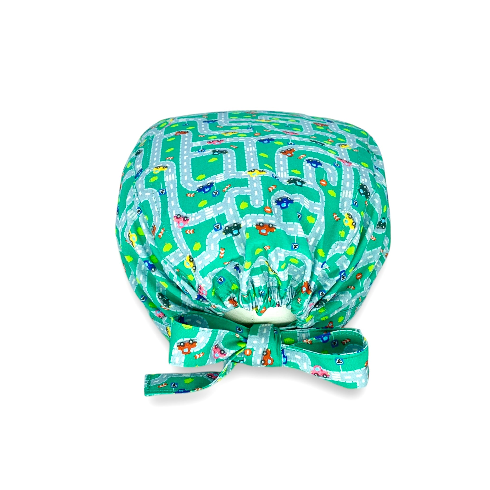 Una cuffietta chirurgica con piccole macchinine colorate in labirinti autostradali con semafori, strisce pedonali ed alberi verdi, su fondo verde.