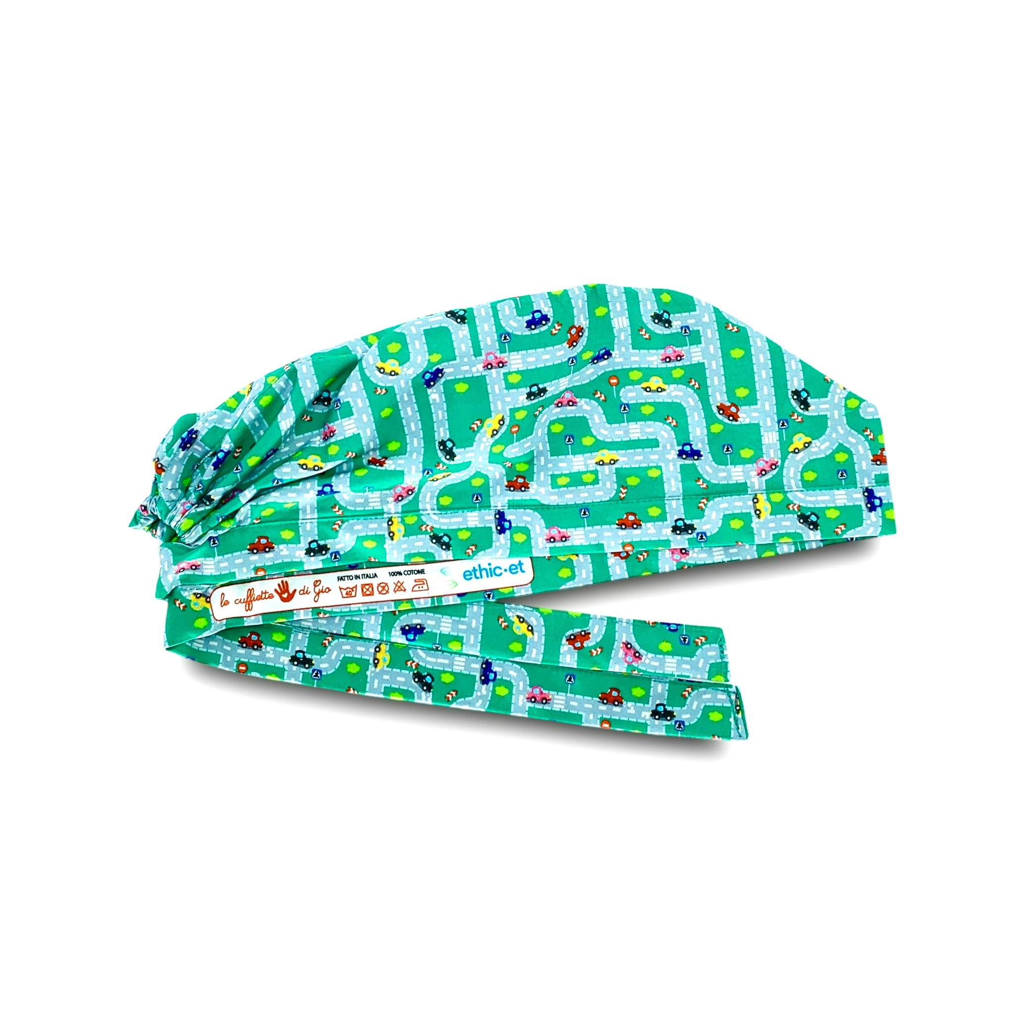 Una cuffietta chirurgica con piccole macchinine colorate in labirinti autostradali con semafori, strisce pedonali ed alberi verdi, su fondo verde.