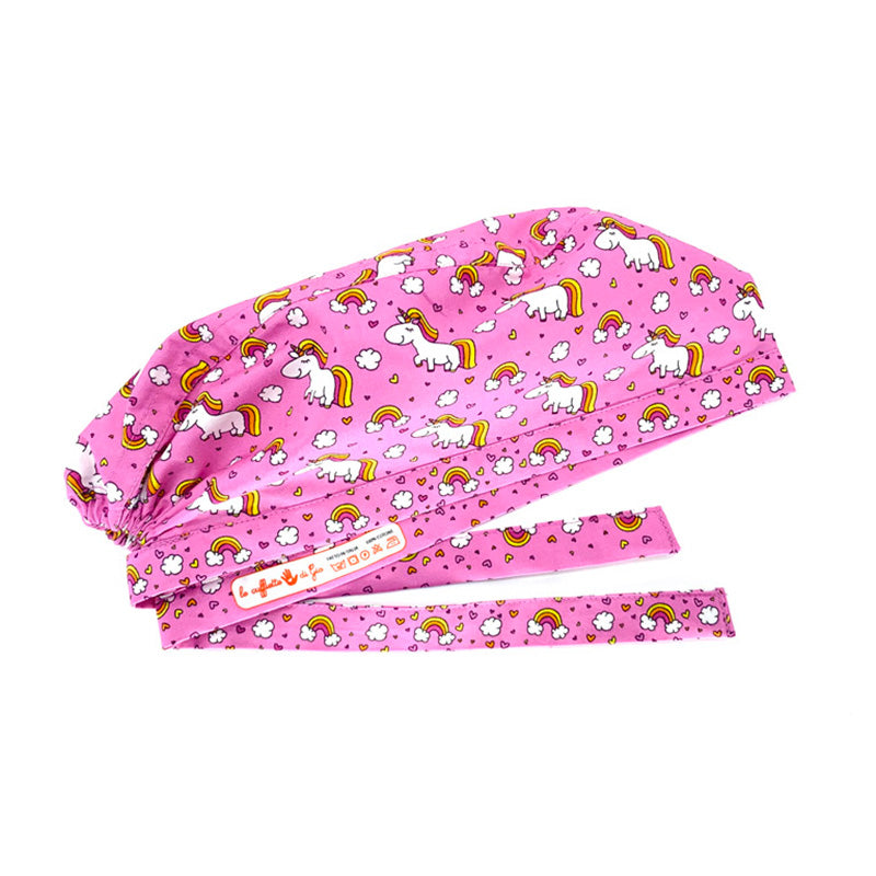 Cuffietta chirurgica con unicorni bianchi tra nuvolette e arcobaleni. Su fondo rosa.
