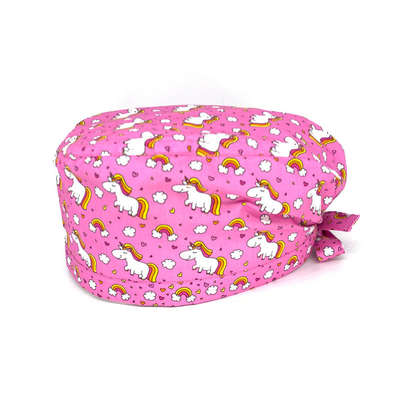Cuffietta chirurgica con unicorni bianchi tra nuvolette e arcobaleni. Su fondo rosa.