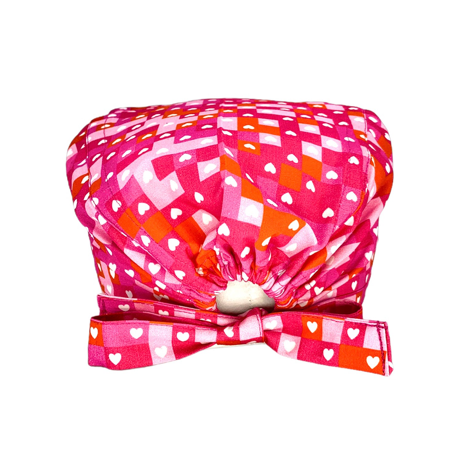 Una cuffietta chirurgica audace nell'abbinamento di rosa, fucsia e rosso alternati come in un puzzle per fare da sfondo a tanti cuoricini bianchi. Vivace e molto elegante