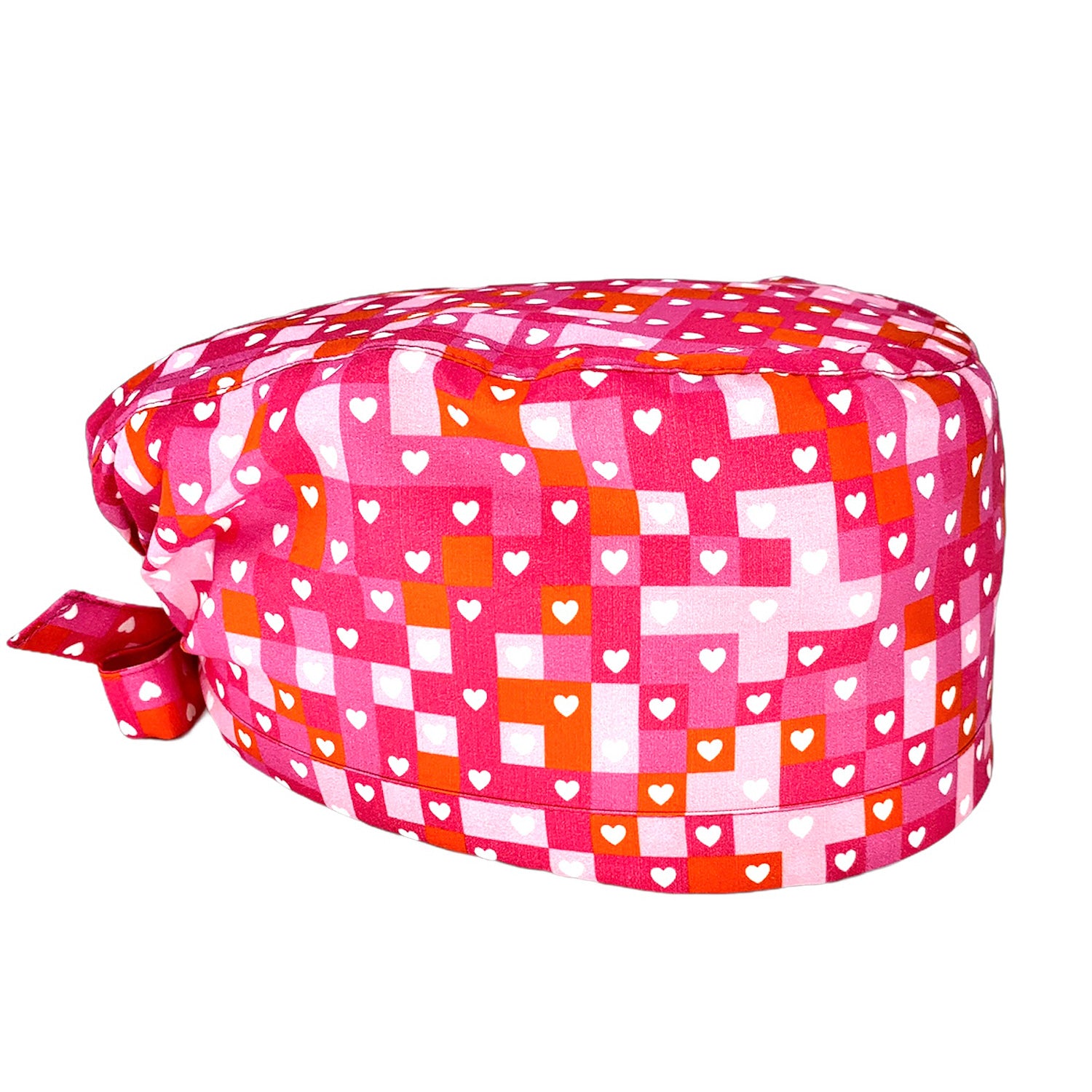 Una cuffietta chirurgica audace nell'abbinamento di rosa, fucsia e rosso alternati come in un puzzle per fare da sfondo a tanti cuoricini bianchi. Vivace e molto elegante