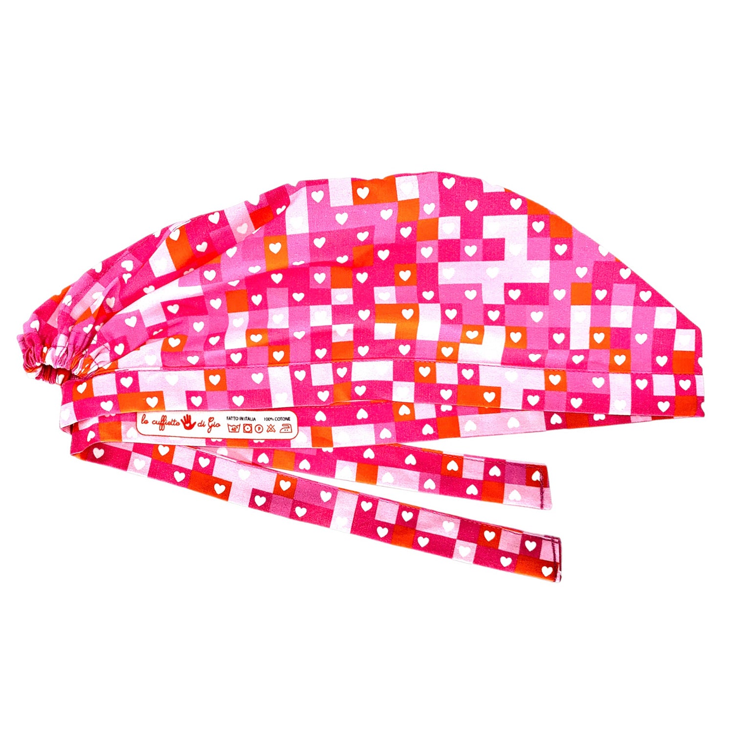 Una cuffietta chirurgica audace nell'abbinamento di rosa, fucsia e rosso alternati come in un puzzle per fare da sfondo a tanti cuoricini bianchi. Vivace e molto elegante