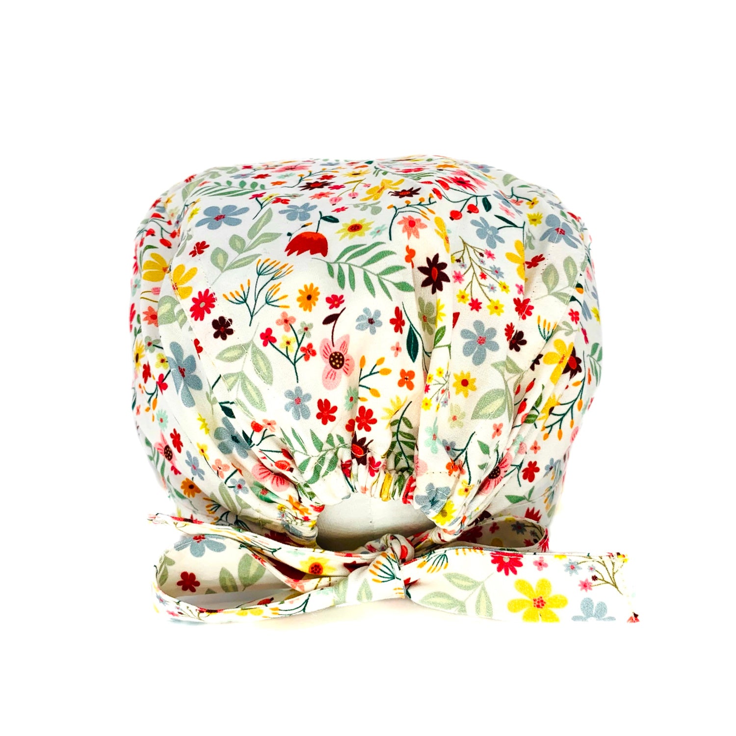 Cuffietta chirurgica con fiori nelle calde tonalità di rossi e gialli che si mescolano a foglie delicate, fiorellini rosa e azzurri per ricordare colori e profumi delle campagne. Sfondo panna