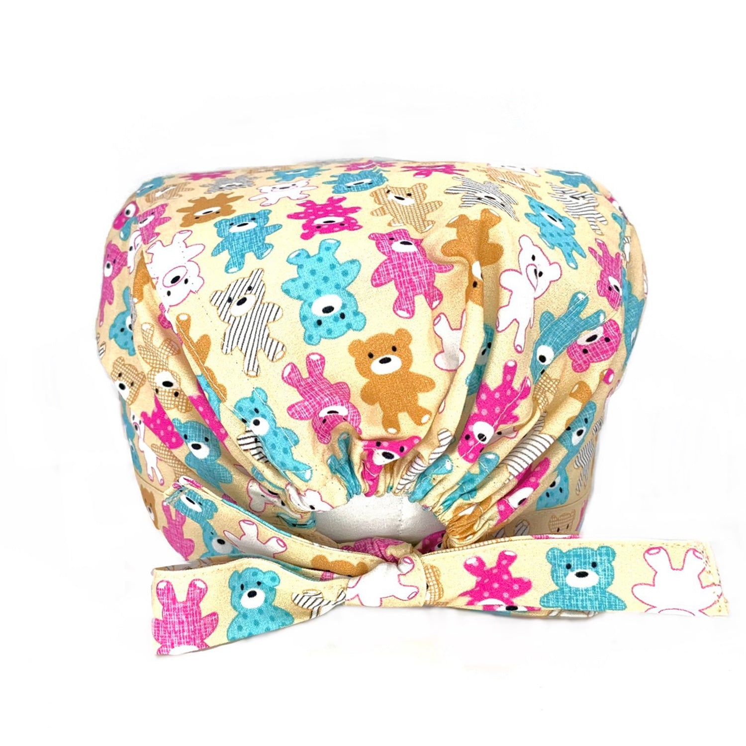 Foto retro cuffietta chirurgica con laccio ed elastico anche per capelli lunghi, con disegnati orsetti di peluche di vari colori tra cui fucsia, azzurro, bainco e marrone chiaro, Foto frontale cuffietta chirurgica con disegnati orsetti di peluche di vari colori su sfondo beige