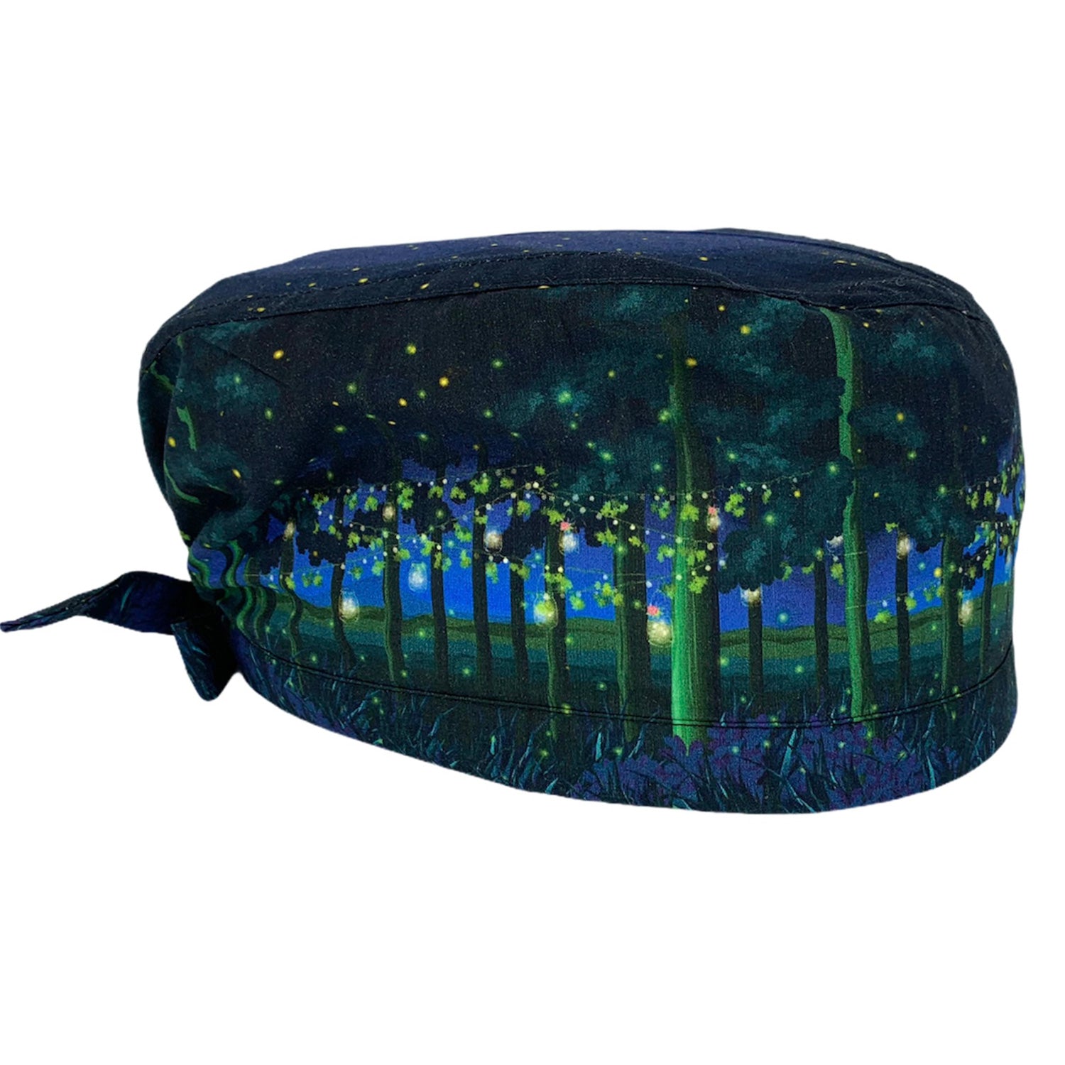 Cuffietta chirurgica che rappresenta un paesaggio notturno di un bosco con alberi a cui sono appesi dei fili, con foglie e fiori e barattoli pieni di lucciole che li illuminano come lanterne; un paesaggio magico e fiabesco