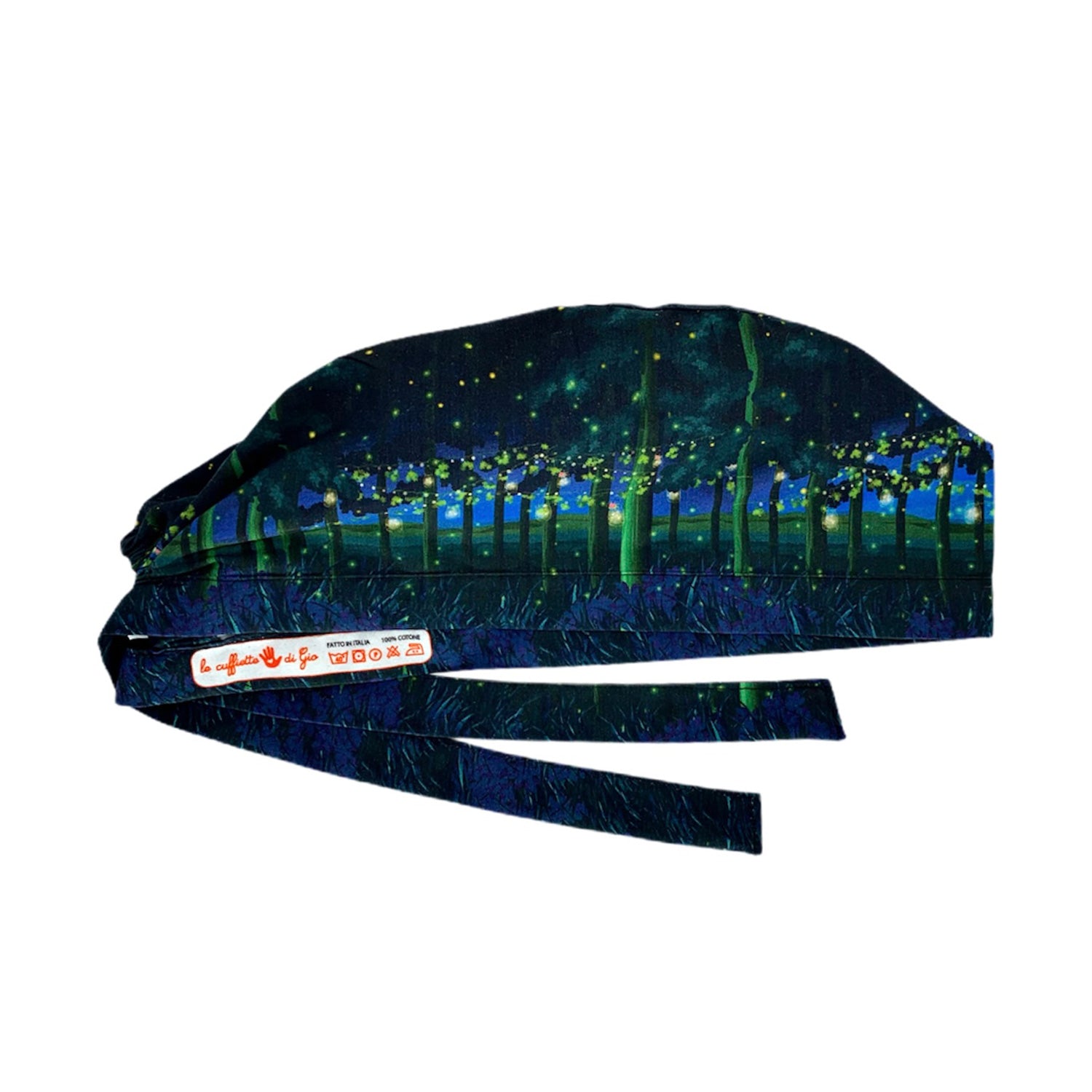 Cuffietta chirurgica che rappresenta un paesaggio notturno di un bosco con alberi a cui sono appesi dei fili, con foglie e fiori e barattoli pieni di lucciole che li illuminano come lanterne; un paesaggio magico e fiabesco