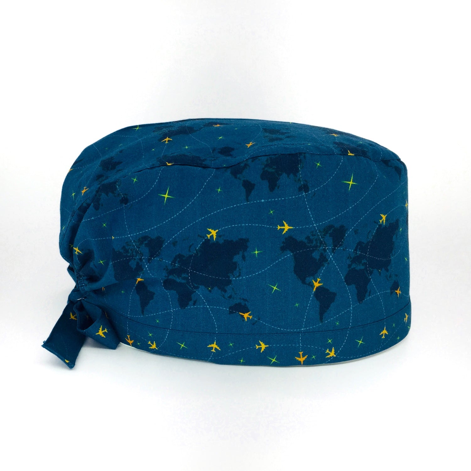 Cuffietta chirurgica con mappamondo e piccoli aerei gialli che tracciano delle linee tratteggiate, sfondo blu avio