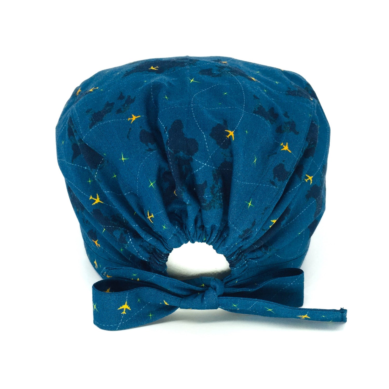 Cuffietta chirurgica con mappamondo e piccoli aerei gialli che tracciano delle linee tratteggiate, sfondo blu avio