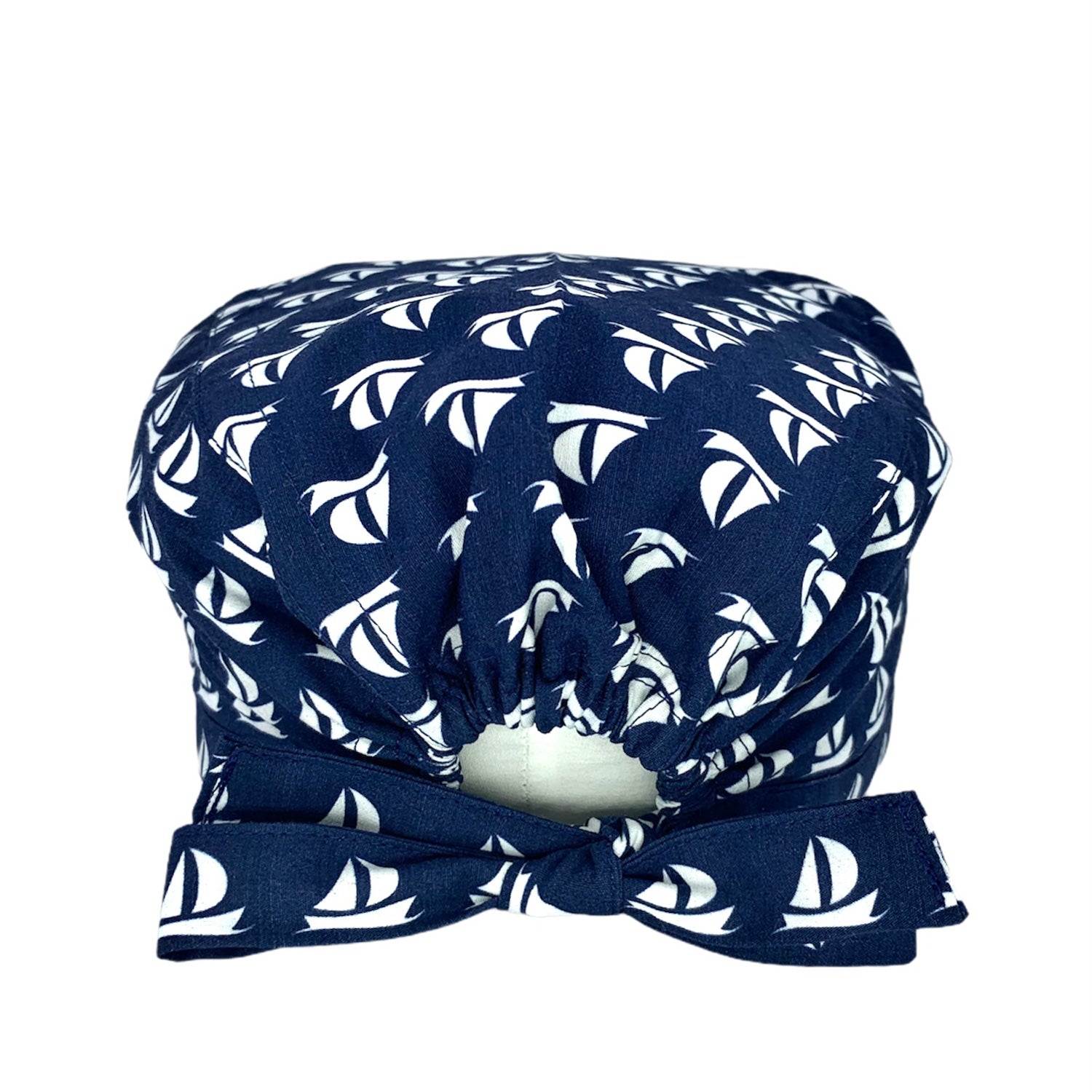 Cuffietta chirurgica blu con piccole barchette a vela bianche stilizzate e organizzate in un elegante pattern geometrico