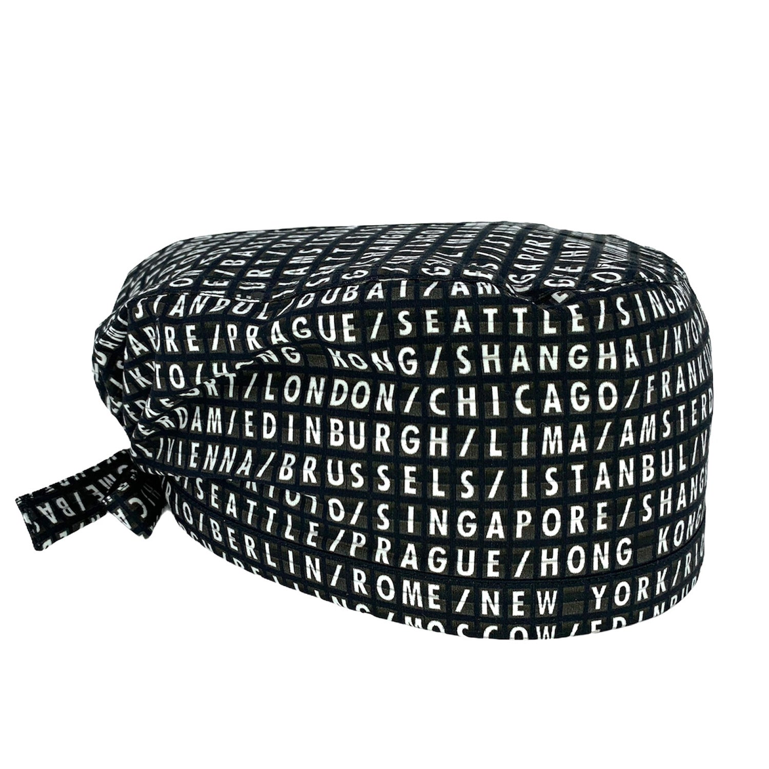 Cuffietta chirurgica con scritte bianche su fondo nero, come un vecchio tabellone aeroportuale, le capitali del mondo si alternano in una lista infinita di posti da visitare.