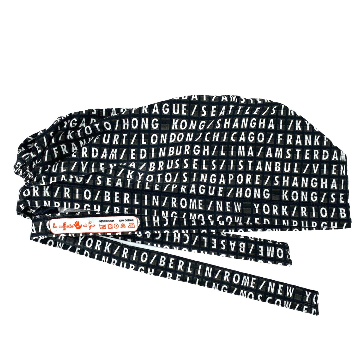 Cuffietta chirurgica con scritte bianche su fondo nero, come un vecchio tabellone aeroportuale, le capitali del mondo si alternano in una lista infinita di posti da visitare.