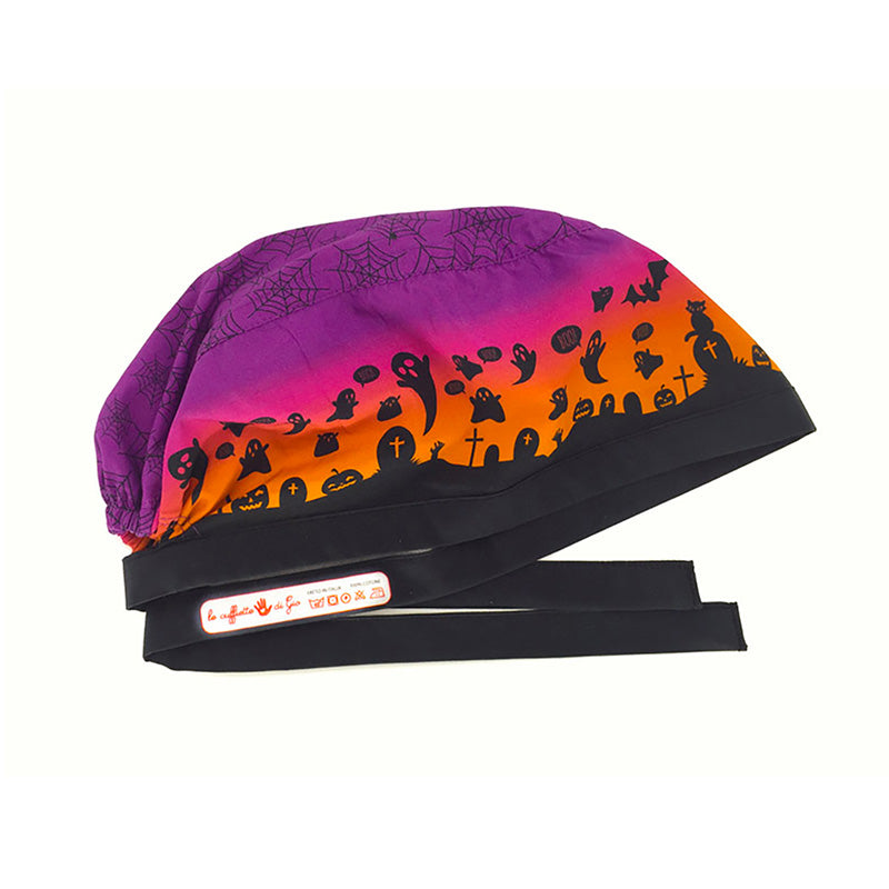 Cuffietta chirurgica con piccoli fantasmi neri e tombe nere sullo sfondo un tramonto che va dall'arancione al viola, colori brillanti per augurare un felice Halloween a chi ti incontra