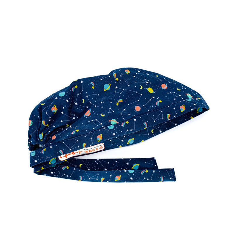 Cuffietta chirurgica con mille micro stelline compongono fantasiose costellazioni, insieme a stelle comete dalla coda variopinta e improbabili pianeti color caramella! sfondo blu