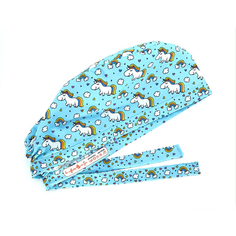 Cuffietta chirurgica con unicorni bianchi tra nuvolette e arcobaleni. Su fondo azzurro
