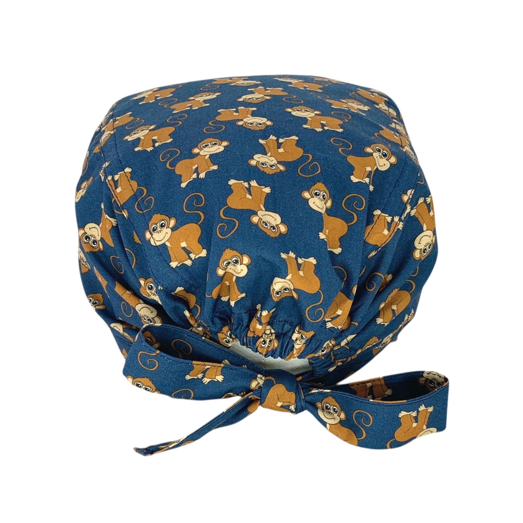 Cuffietta chirurgica con simpatiche scimmiette marroni, sorridenti e con la coda lunga arricciata, alternate a testa in giù o diritte; sfondo blu
