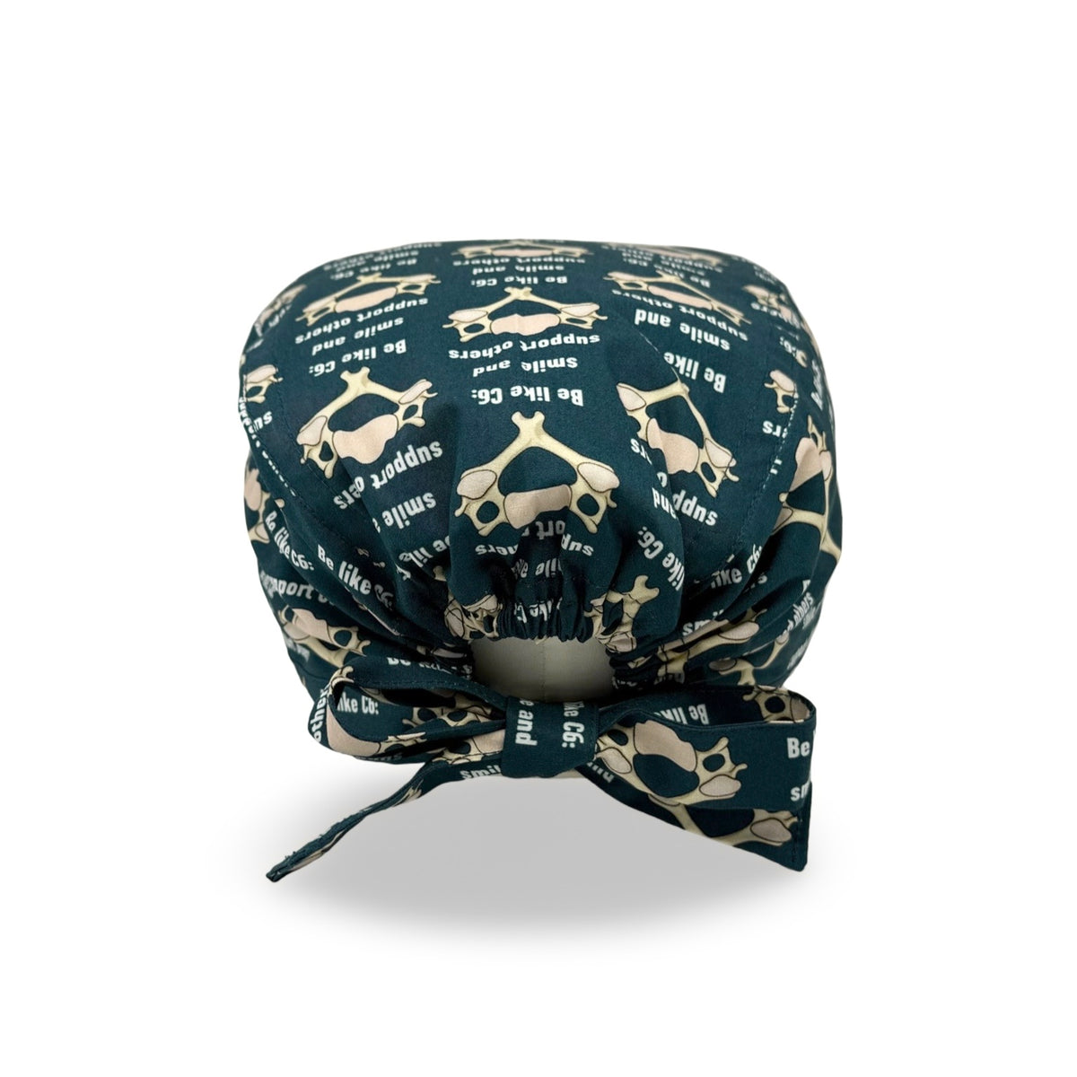 In questa cuffietta chirurgica un meme si trasforma in un simpatico pattern, ideale per neurochirurghi e per chi vuole promuovere simpaticamente lo spirito di squadra, una vertebra C6 stilizzata sembra un mostriciattolo sorridente e si abbina alla frase in inglese "sii come C6: sorridi e supporta gli altri" su sfondo blu petrolio