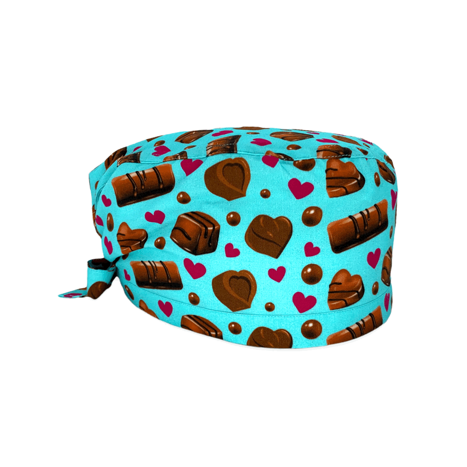 Una cuffietta chirurgica dedicata agli amanti del cioccolato: praline e cioccolatini con piccoli cuori a contrasto su sfondo azzurro o rosa