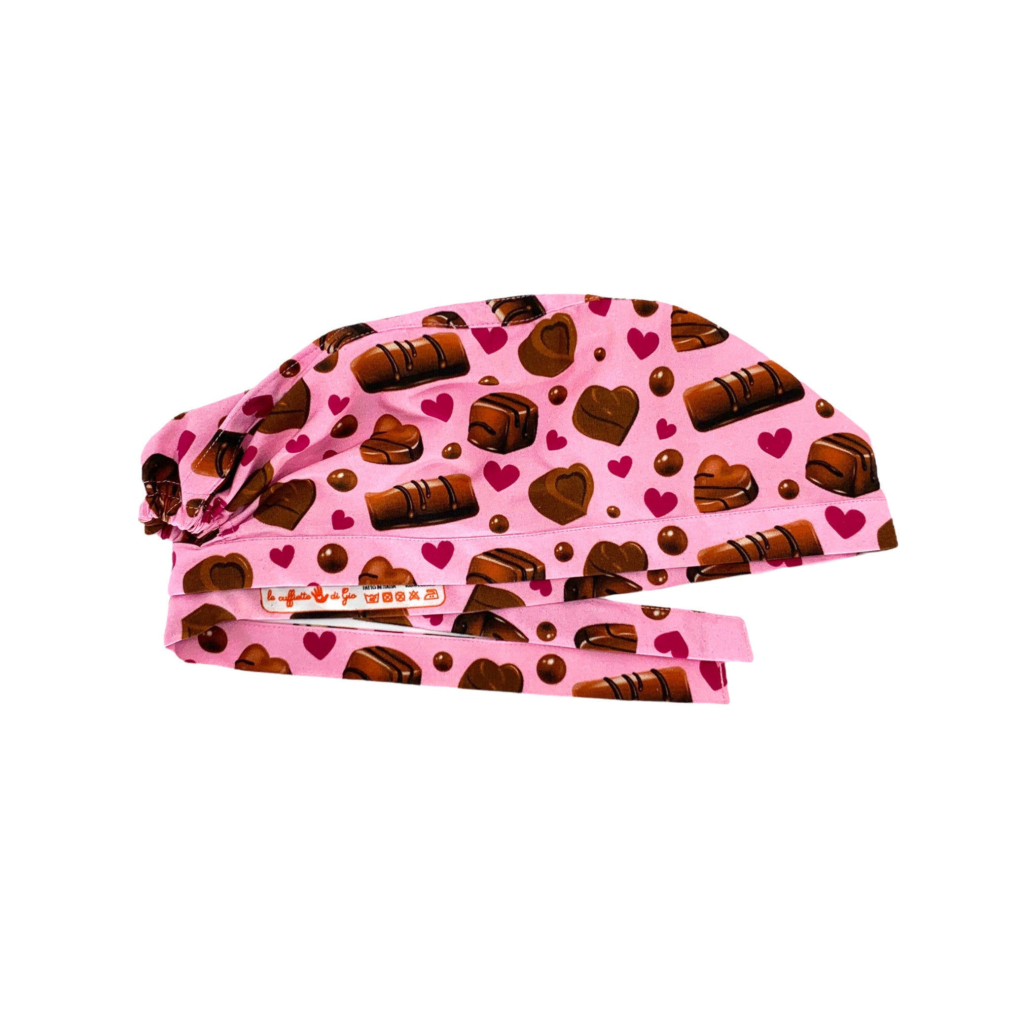 Una cuffietta chirurgica dedicata agli amanti del cioccolato: praline e cioccolatini con piccoli cuori a contrasto su sfondo rosa