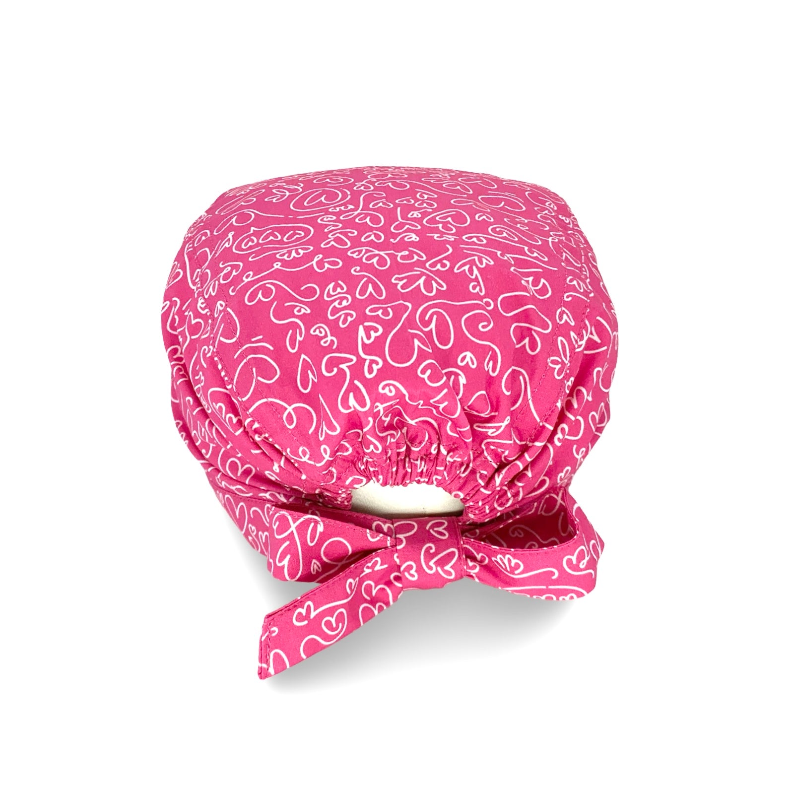 Un'elegantissima fantasia per questa cuffietta chirurgica, tappezzata di cuoricini scarabocchiati a mano con un tratto bianco su base tinta unita lilla, fucsia o turchese.