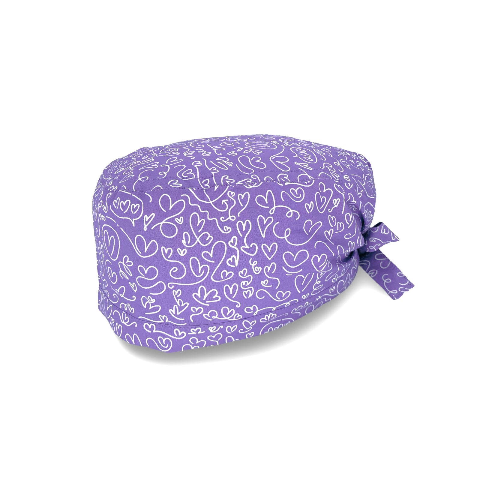Un'elegantissima fantasia per questa cuffietta chirurgica, tappezzata di cuoricini scarabocchiati a mano con un tratto bianco su base tinta unita lilla, fucsia o turchese.
