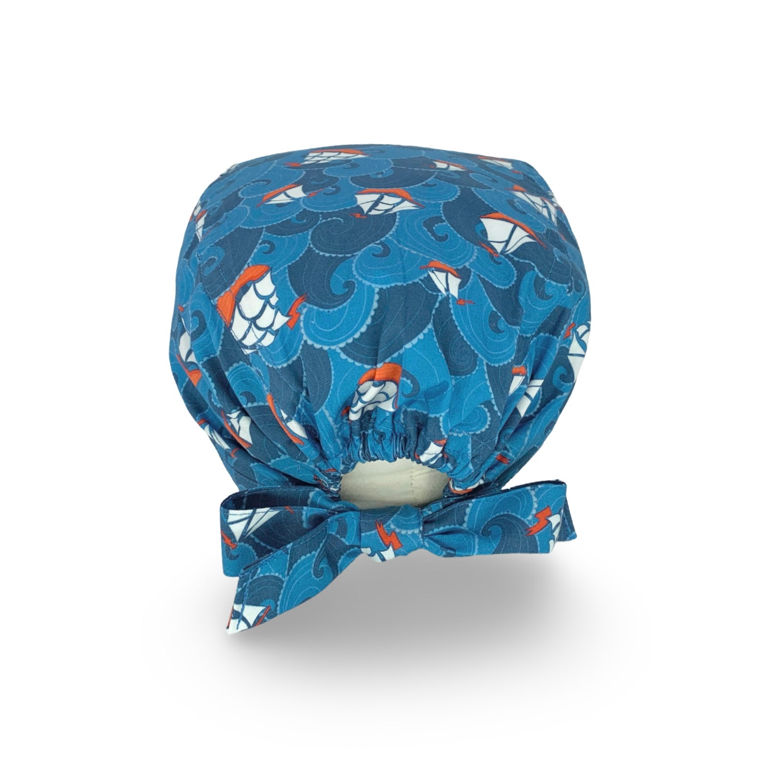 Una cuffietta chirurgica a tema marino, con onde e velieri stilizzati; il tutto declinato in modo eleganti nei toni dell'azzurro e blu medio, con un tocco di rosso e bianco.