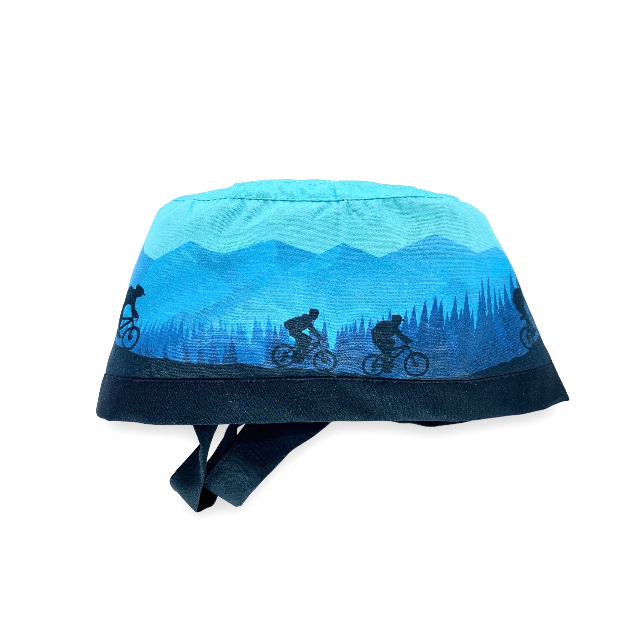 Cuffietta chirurgica che rappresenta una gita in bicicletta fra boschi e montagne; colore prevalente azzurro cielo con figure blu di ciclisti montagne alberi nel retro blu medio