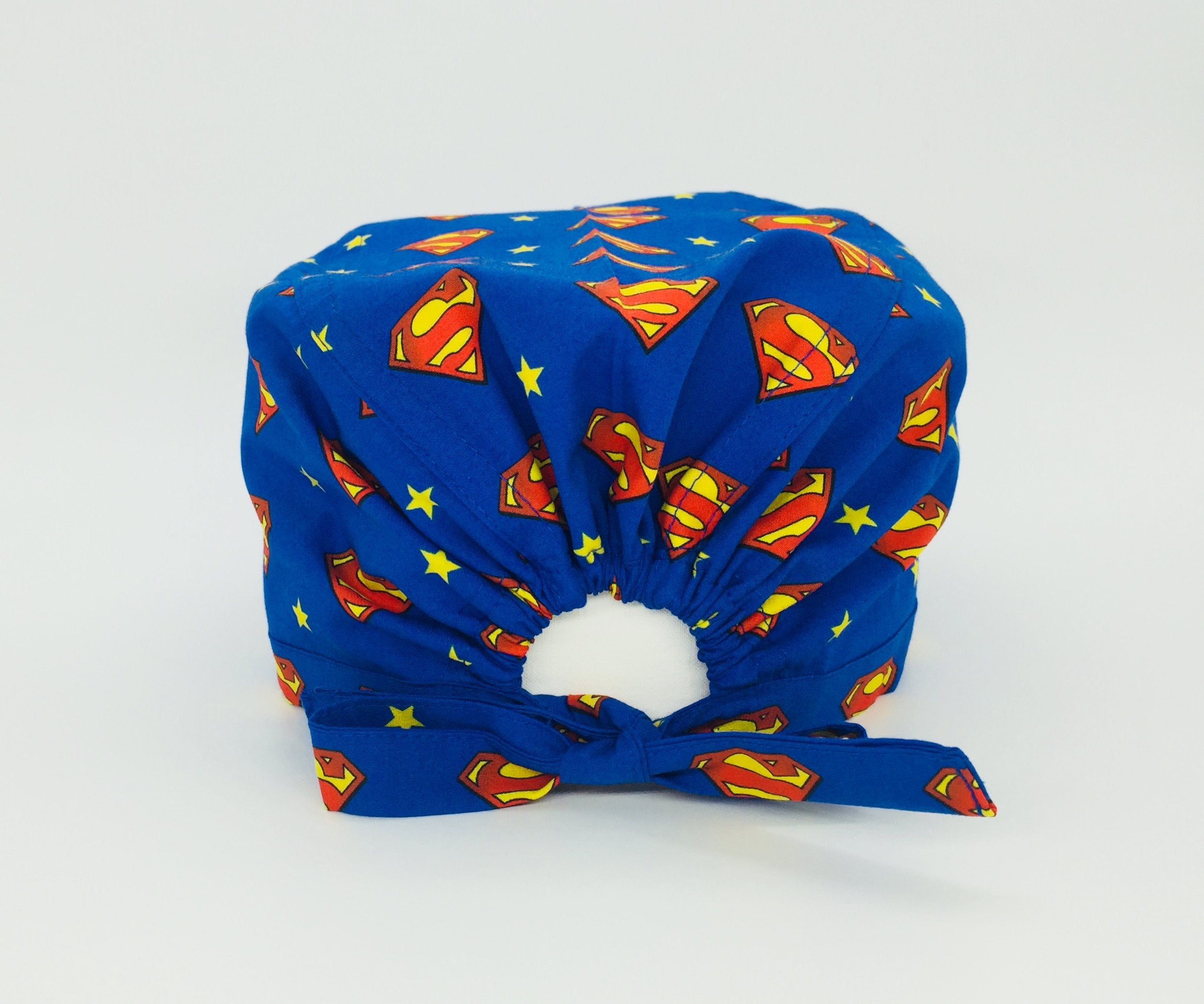 Cuffietta chirurgica blu cobalto con logo di Superman alternato a una stellina gialla in un semplice pattern geometrico